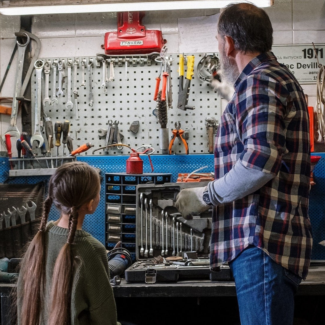 Père et fille dans atelier de bricolage avec outils professionnels
